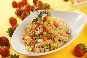 Fusilli pasta salad with ham, pumpkin, papaya, strawberry and broccoli.