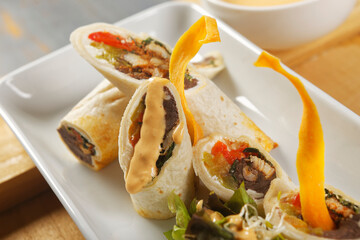 Chicken wrap with beans and peppers accompanied by salad and cheddar cheese dressing.