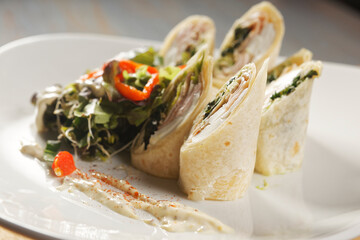 Wrap of ham, fresh cheese and spinach accompanied with lettuce and bell pepper salad.