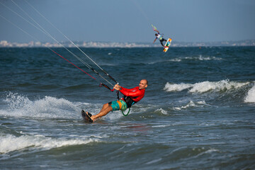 Kitesurfing on the waves of the sea in Mui Ne beach, Phan Thiet, Binh Thuan, Vietnam. Kitesurfing, Kiteboarding action photos. Kitesurf In Action against vietnamese boats