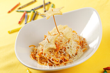 Noodle pasta with tomato sauce and parmesan cheese decorated with a star-shaped cookie.