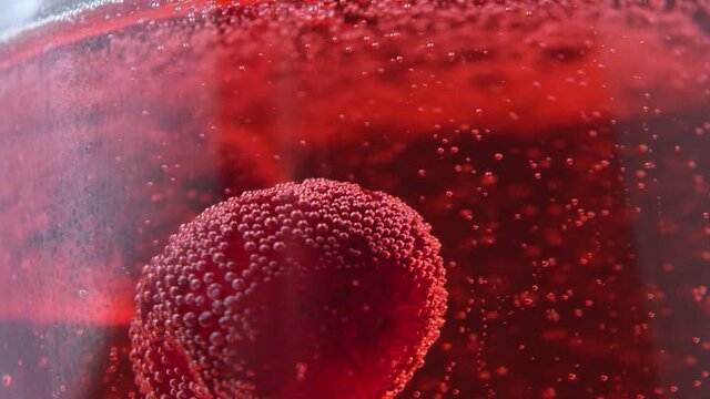 A cherry is floating in a red drink