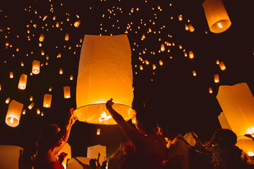 Loy krathong festival, thai new year party with floating lanterns release in the night sky