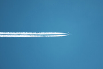 Close up on airplane contrail against clear blue sky.