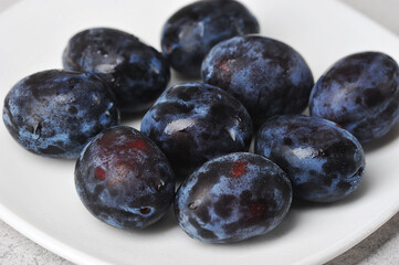juicy ripe black and blue plums on a plate