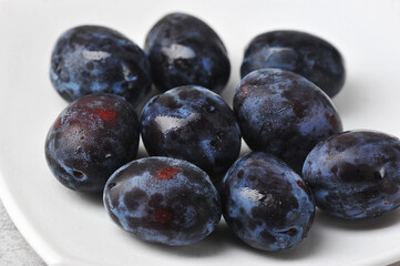 juicy ripe black and blue plums on a plate