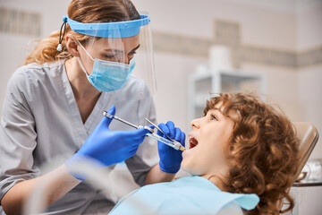 Professional dentist is giving anesthesia to a child