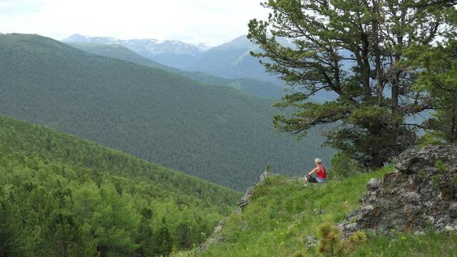 Ashram yoga. Adventures in nature. A young woman is doing Ashram yoga techniques in the mountains, trying to keep her balance on an uneven surface. Siberia.