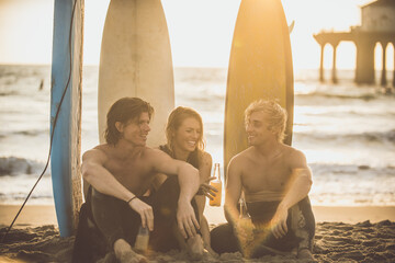 Three surfers relaxing on the beach after sport