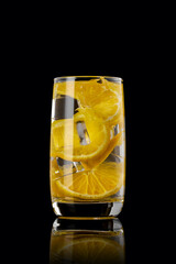 A glass of orange lemonade on a black background.