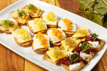 Snacks of toasted bread with Mozarella cheese, fresh cheese and Manchego cheese with strawberry, kiwi and pineapple marmalade.