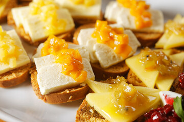 Snacks of toasted bread with Mozarella cheese, fresh cheese and Manchego cheese with strawberry, kiwi and pineapple marmalade.