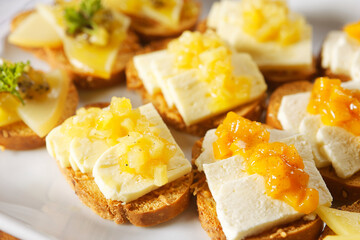 Snacks of toasted bread with Mozarella cheese, fresh cheese and Manchego cheese with strawberry, kiwi and pineapple marmalade.