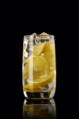 A glass of lemon lemonade on a black background.