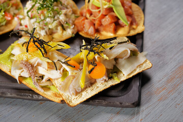 Tuna, shrimp and octopus toast snacks with radish, cucumber and avocado.