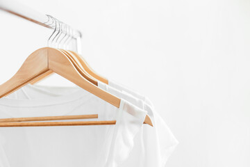 Wooden hangers with white blouses on the counter.