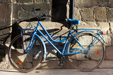 Blue vintage bicycle leaning against a stone facade