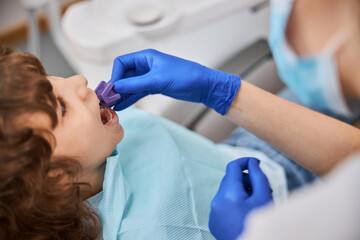 Pediatric dentist using bite block while treating a kid