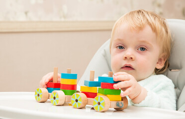 An inquisitive kid plays with educational toys while sitting at his children's table. Close up. Copy space