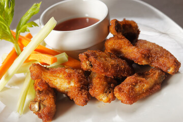 Chicken wings with carrot and celery accompanied by buffalo sauce.