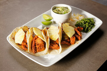 Tacos al pastor with guacamole, onion, coriander, pineapple and lemon.