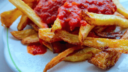 french fries covered with hot organic  tomato sauce closeup in the white plate