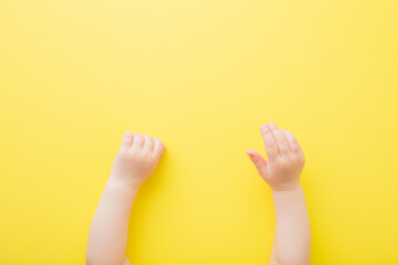 Baby hands on yellow table background. Closeup. Point of view shot. Top down view.