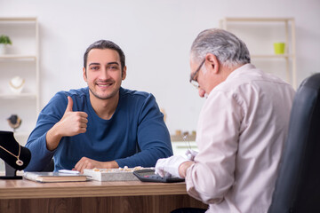 Young man visiting old male jeweler