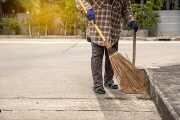 Workers are sweeping the pavement with broom that fall on the street. Street sweeper cleaning road