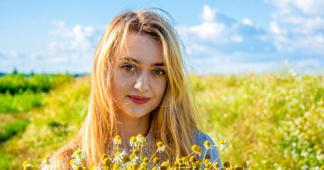 simple portrait of a beautiful smiling girl with a large bouquet of wildflowers. photo against a background of blue sky and green field.