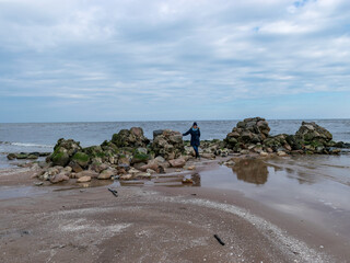 woman silhouette on a rocky sea shore, early spring