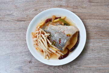 spicy boiled Tilapia or mango fish tail with shimaji mushroon in tom yum soup on plate