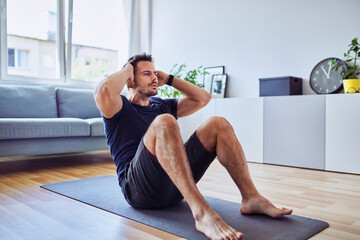 Sporty man doing sit-ups exercise during home workout - Powered by Adobe