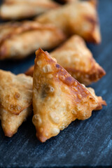 Fried Samosa (samoosa) triangle pastries on a dark surface