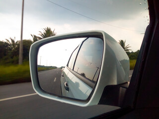 Naklejka premium The view in the car side mirror When the weather is closed, the rain is about to fall in the rural roads of Thailand.