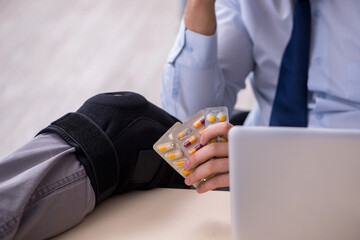 Young leg injured employee working in the office