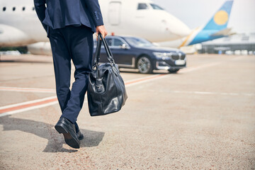 Businessman with a carry-on walking towards an aircraft