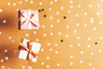 Polka dot pattern gift box with ribbon falling on beige or gold  background