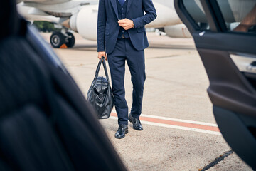 Elegant man carrying a bag walking to a car