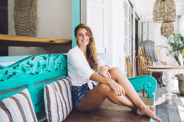 Cheerful woman having rest at bench on veranda