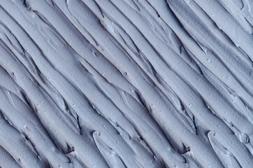 Gray bentonite facial clay (alginate mask, face cream, body wrap) texture close up, selective focus. Abstract background with brush strokes.