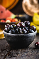Jaboticaba or jabuticaba, Brazilian and South American fruit, in a clay pot. with tropical fruits in the background.