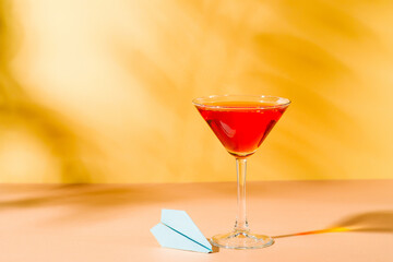 Vacation red cocktail  martini in glass with blue plane  on yellow background