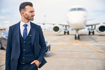Young businessman posing in front of a plane