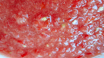 Red liquid organic tomato sauce in a white pot 