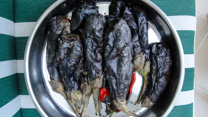 Grilled and roasted whole black eggplants on the metal pot