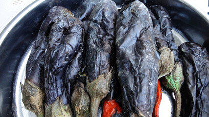 Obraz premium Grilled and roasted whole black eggplants on the metal pot