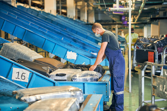 Baggage Handler Checking A Suitcase In The Sorting Room