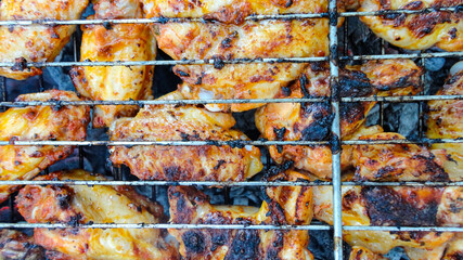 Chicken wings on barbecue grill with fire close up. Chicken meat on the grill