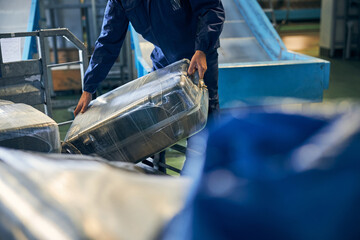 Luggage handler holding a suitcase while sorting bags